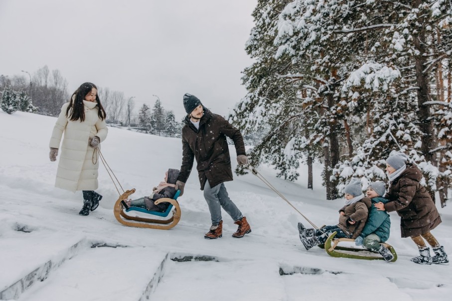 Eine Familie genie&szlig;t einen Spaziergang  durch verschneiten Wald im Winterurlaub und zieht einen Schlitten mit.  &copy; Shutterstock