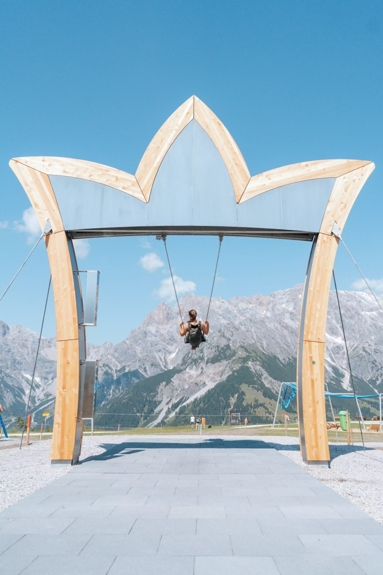 Person schaukelt unter h&ouml;lzerner Krone vor malerischem Bergpanorama von Hochk&ouml;nig. &copy;TVB_Hochk&ouml;nig