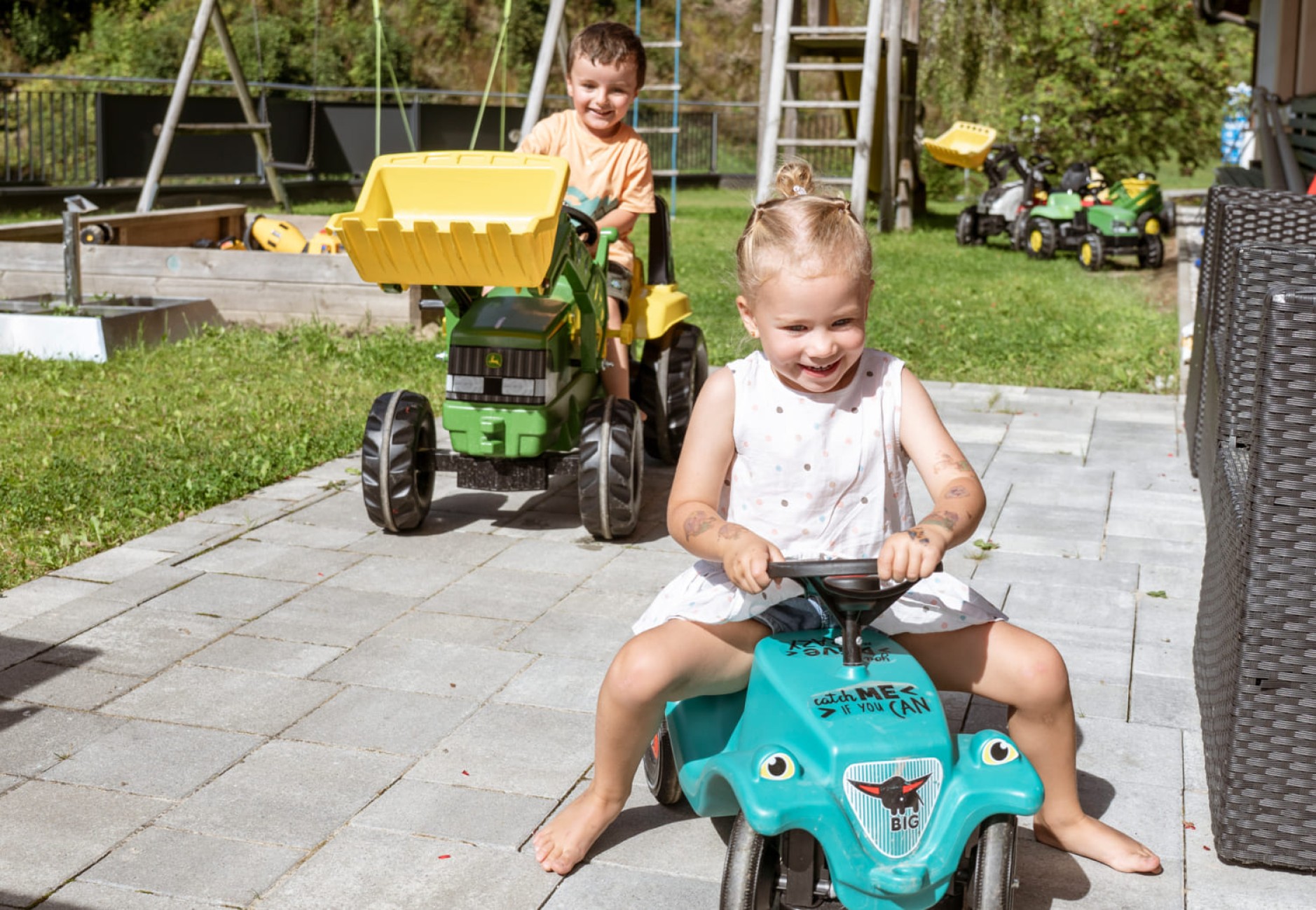 Kinder spielen im Garten vom Hotel Bachschmied mit Fahrzeugen.