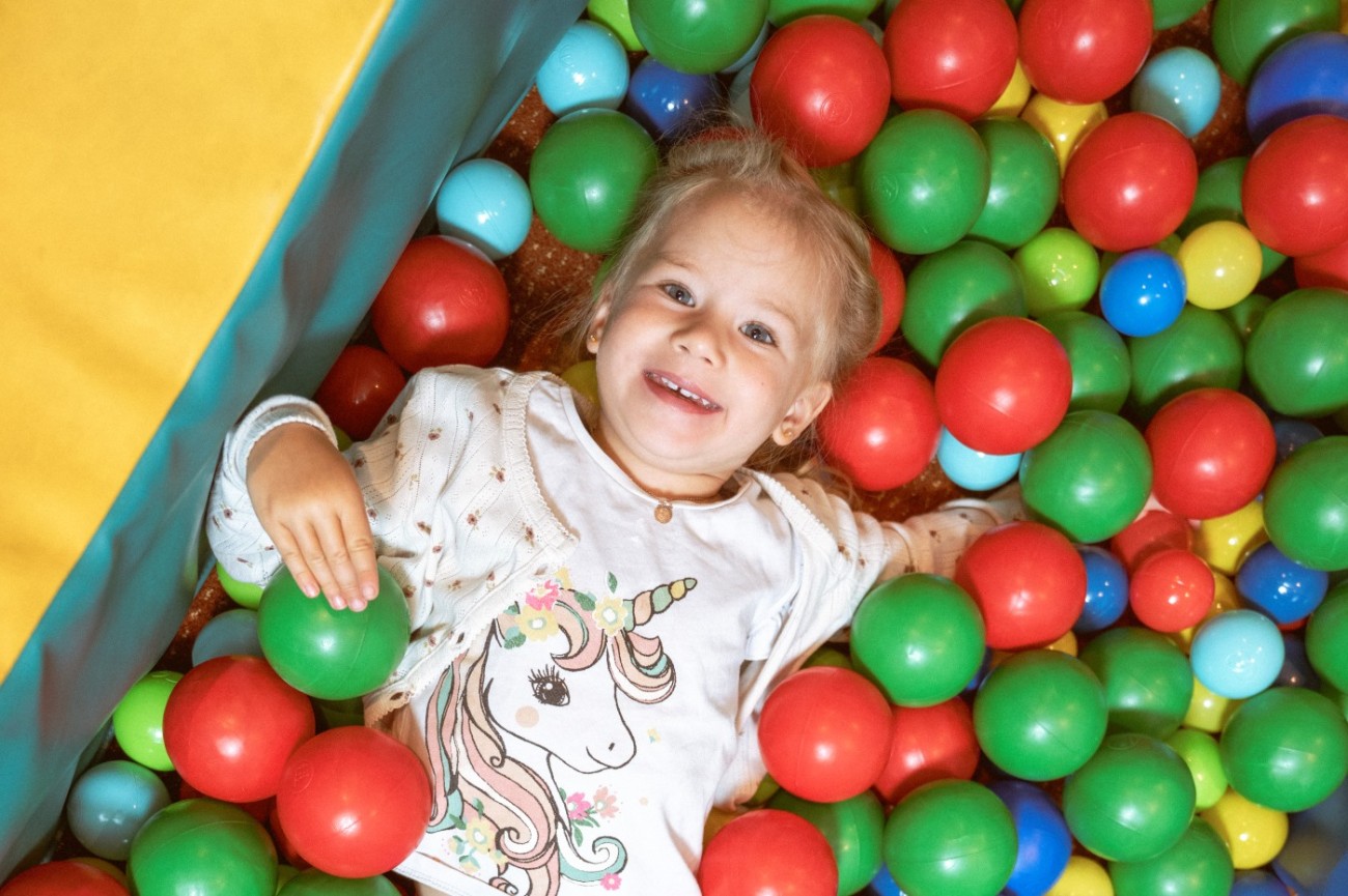 Kleines M&auml;dchen lacht im B&auml;llbad vom Hotel Bachschmied in Maria Alm.