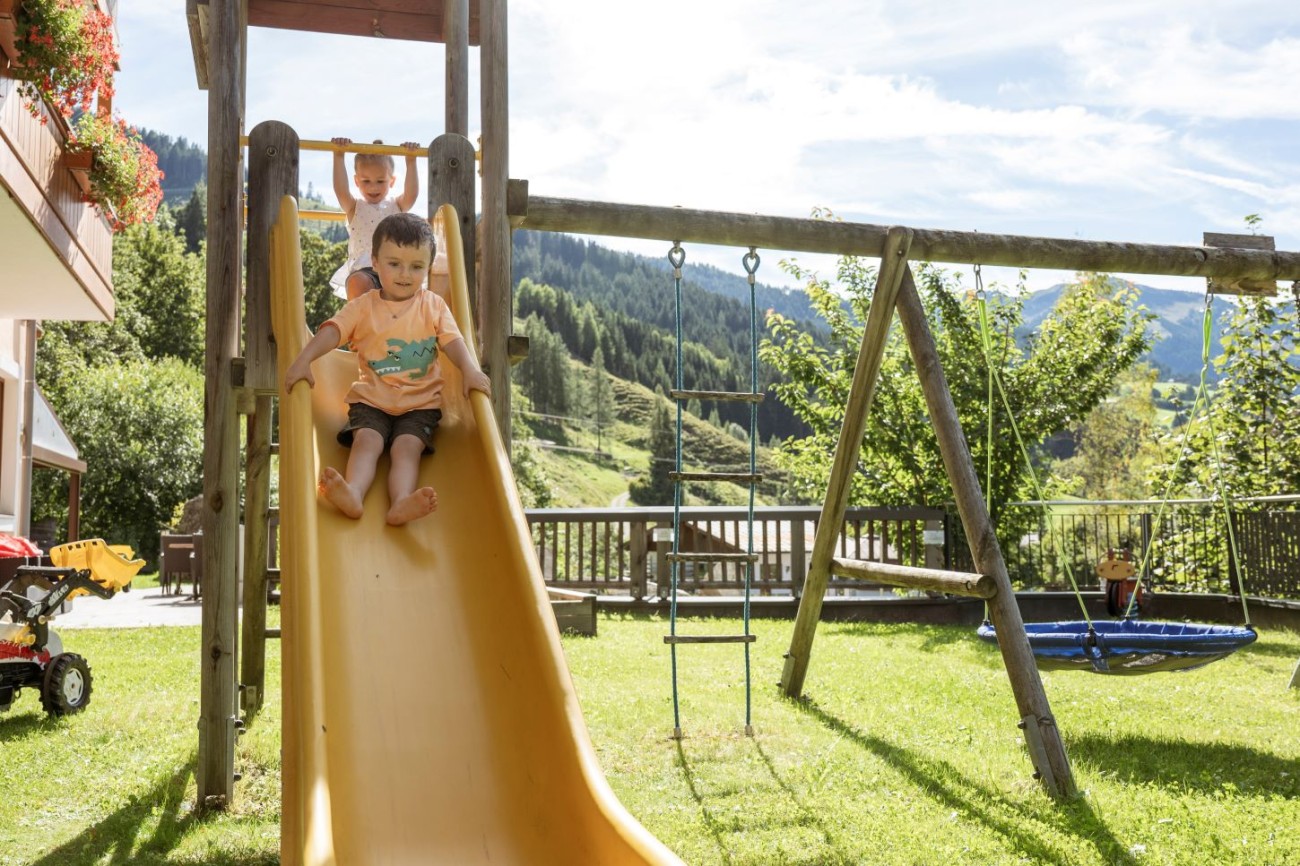 Kinder haben Spa&szlig; auf der Rutsche im Garten des Hotel Bachschmied im Familienurlaub.
