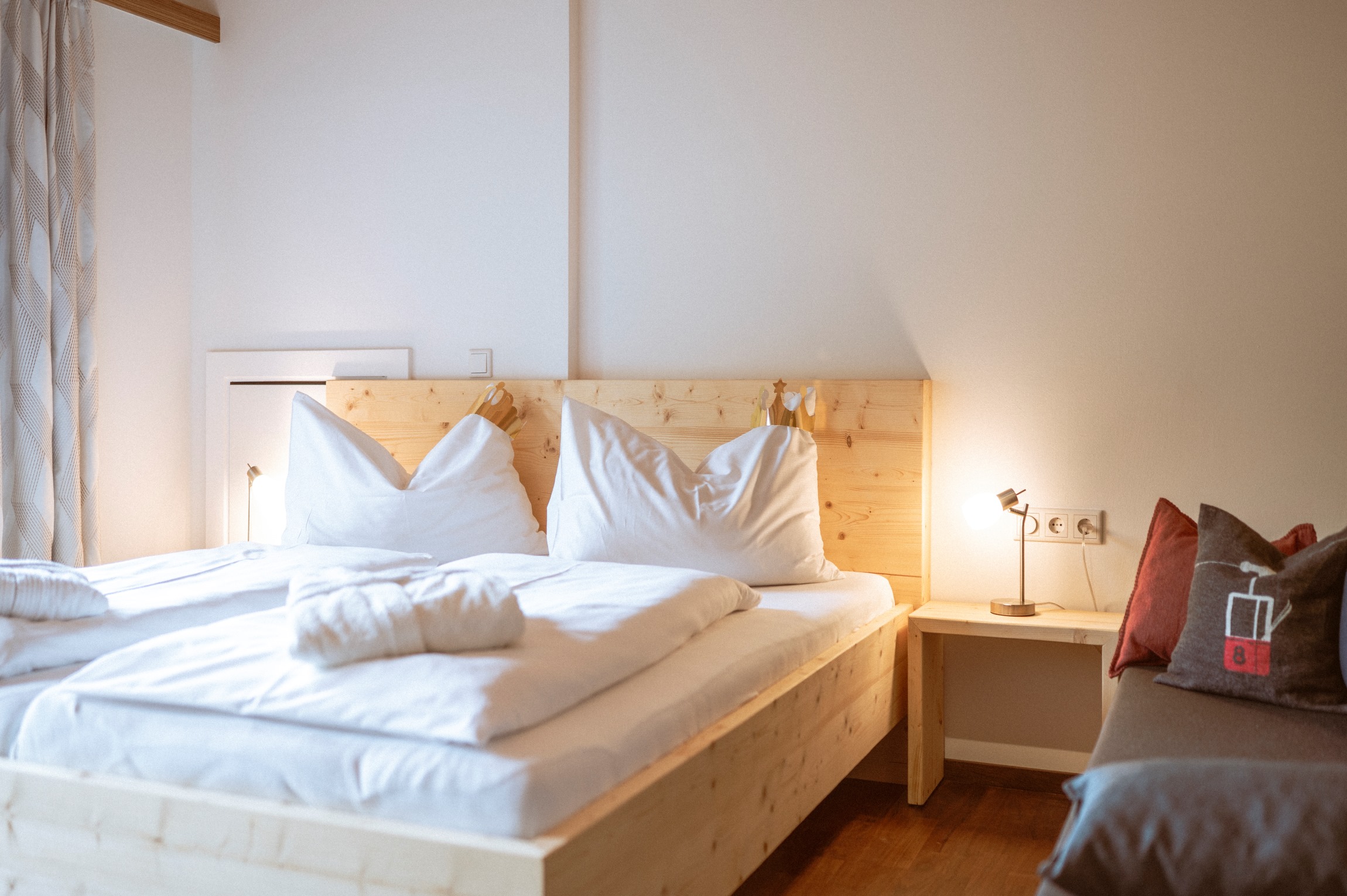 Gemütliches Schlafzimmer mit Doppelbett und Nachttischlampe auf einem Holztisch