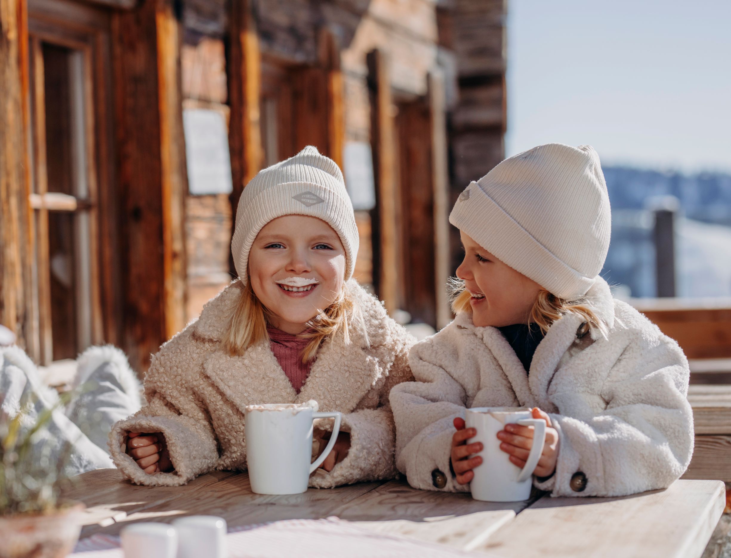 Zwei Kinder sitzen draußen lächelnd und trinken Kakao. © SalzburgerLand Tourismus-Verena Schierl