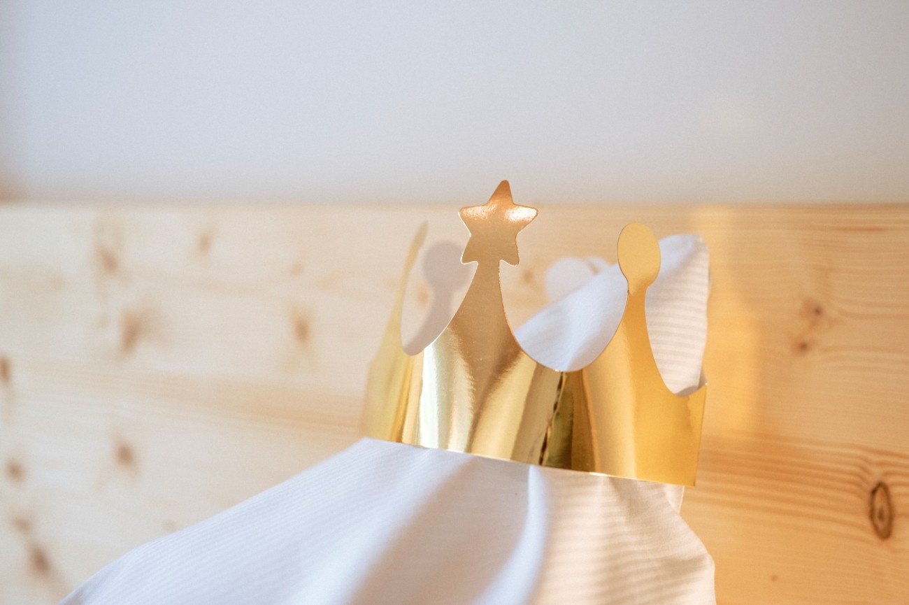 Goldene Papierkrone mit Sternen am Bett im Hotel Bachschmied in Maria Alm.