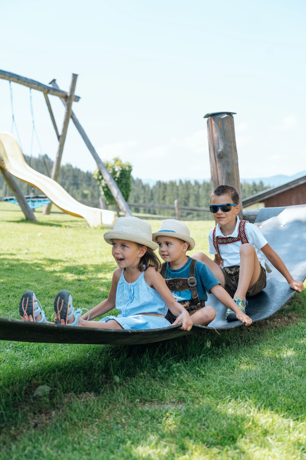 Drei Kinder spielen lachend auf einer Rutsche im Freien im Familienurlaub im Bachschmied. &copy;TVB_Hochk&ouml;nig