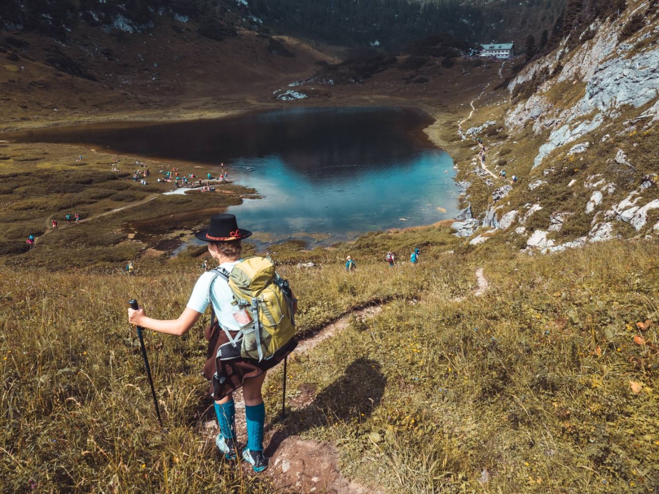 Eine Wanderin mit Rucksack blickt auf einen Bergsee in alpiner Landschaft am Hochk&ouml;nig. &copy;TVB_Hochk&ouml;nig