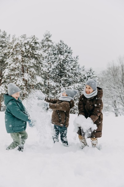 Drei Kinder spielen fr&ouml;hlich im Schnee vor schneebedeckten B&auml;umen im Skiurlaub mit der Familie in Maria Alm. &copy;Shutterstock