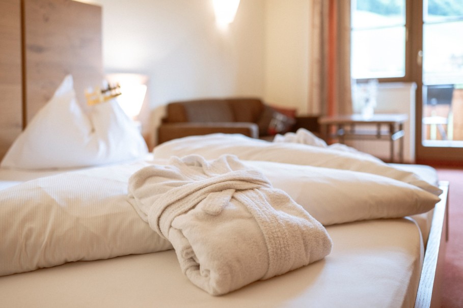 Ein zusammengelegter Bademantel liegt auf dem Hotelbett im gem&uuml;tlichen Doppelzimmer im Bachschmied.