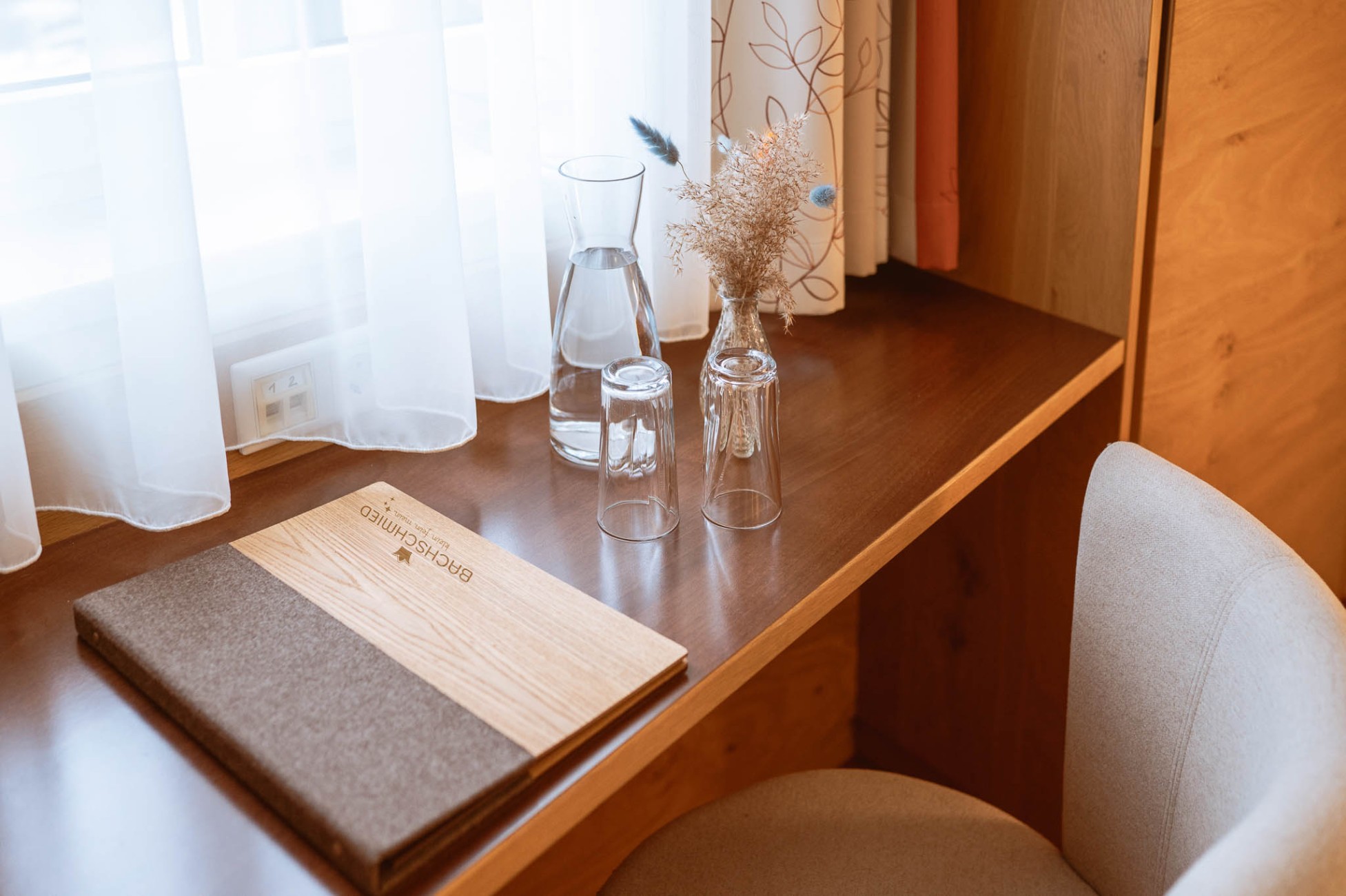 Schreibtisch mit G&auml;stebuch und Wasserkaraffe im Hotel Bachschmied.