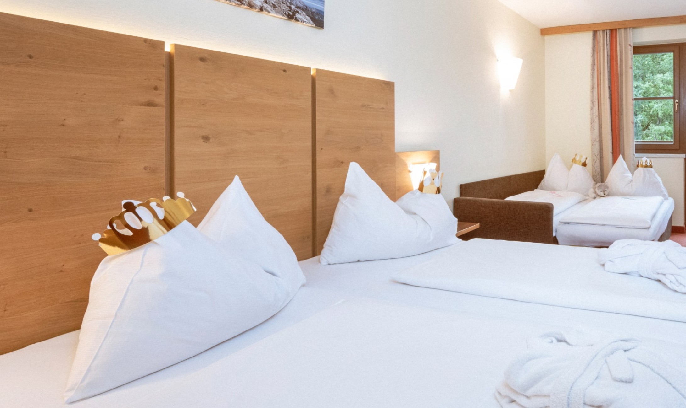 Ein gem&uuml;tliches Hotelzimmer mit zwei Betten, Sofas und Holzverkleidungen an der Wand im Bachschmied.