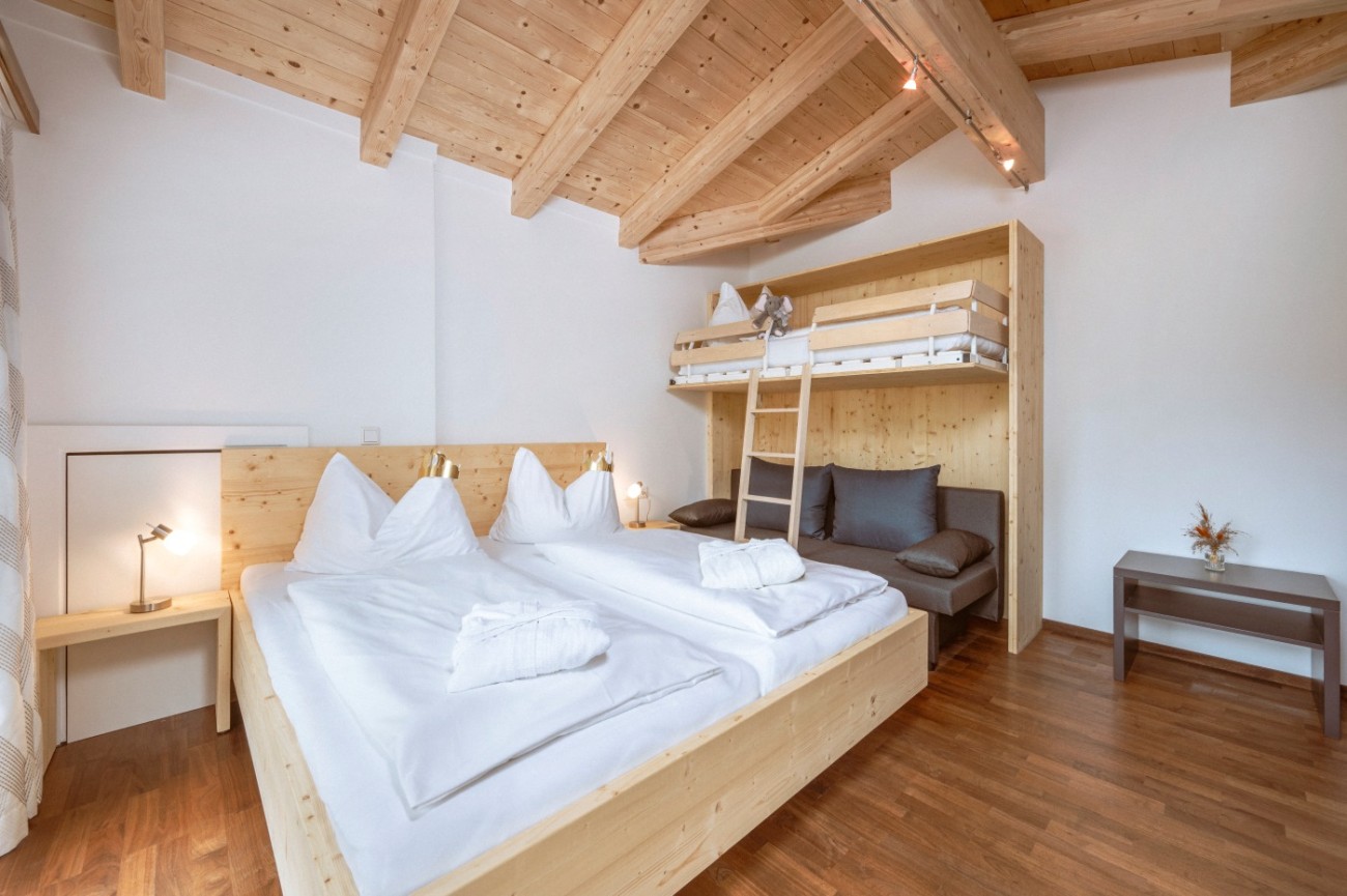 Helles Schlafzimmer mit Holzbetten, Doppelbett und ein Stockbett mit Leiter im Bachschmied.