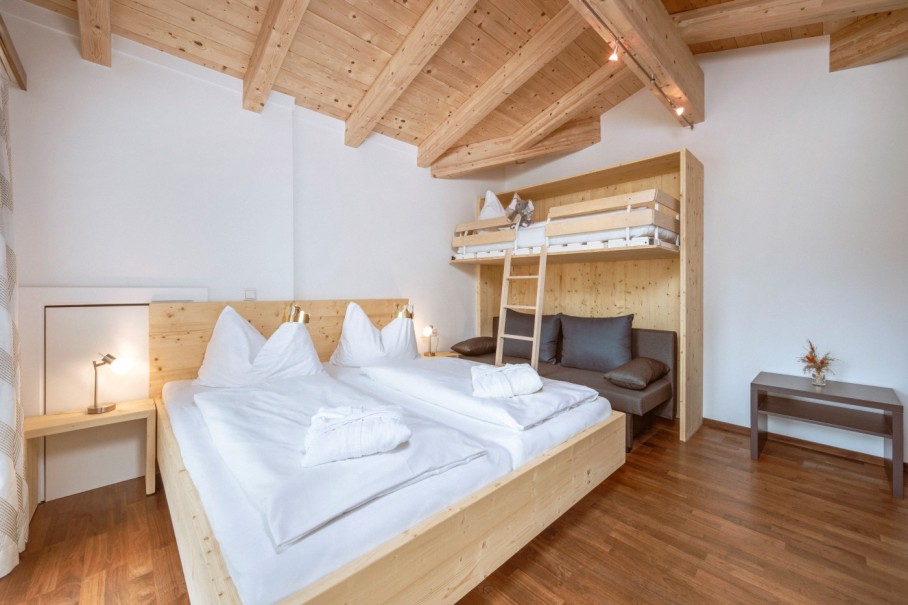 Helles Schlafzimmer mit Holzbetten, Doppelbett und ein Stockbett mit Leiter im Bachschmied.