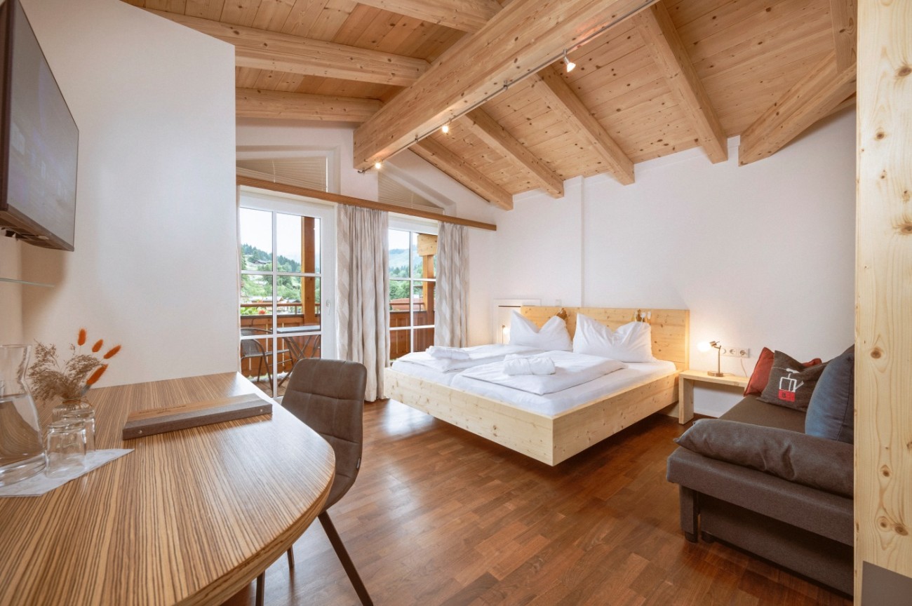 Helles Zimmer mit Holzbalkendecke, gem&uuml;tlichem Bett, Sofa und Balkonblick im Doppelzimmer im Bachschmied.